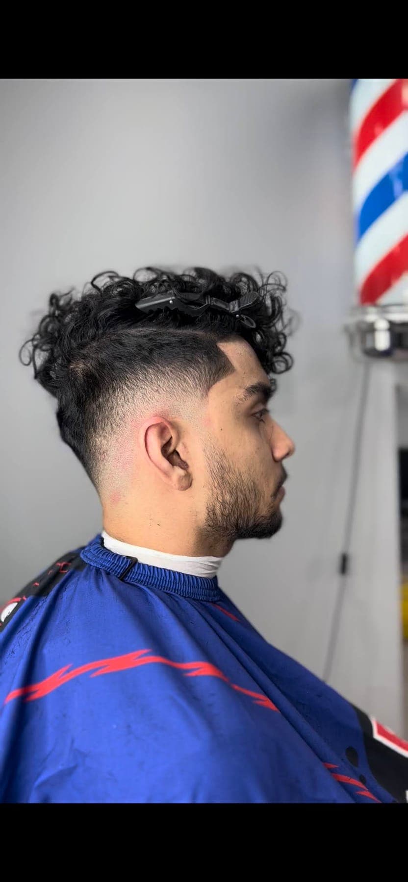 Curly top with a low taper, barber pole behind